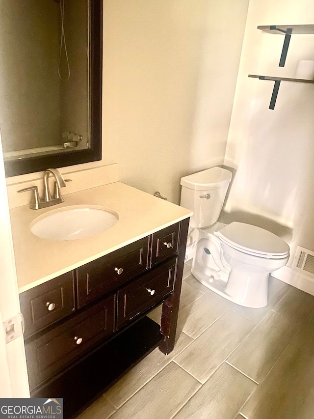 bathroom featuring visible vents, toilet, and vanity