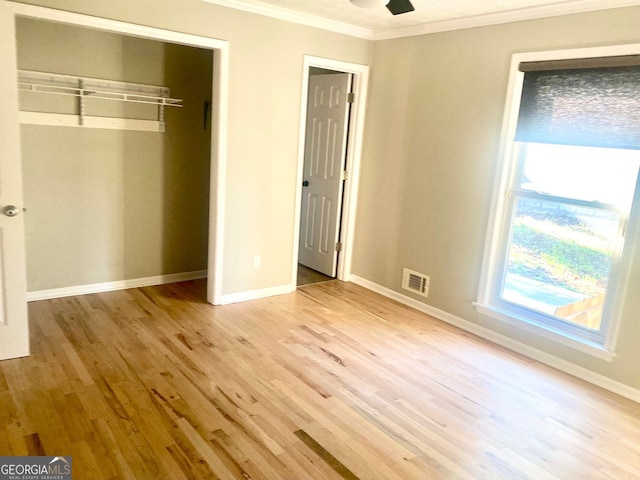 unfurnished bedroom featuring visible vents, light wood-style flooring, a closet, crown molding, and baseboards