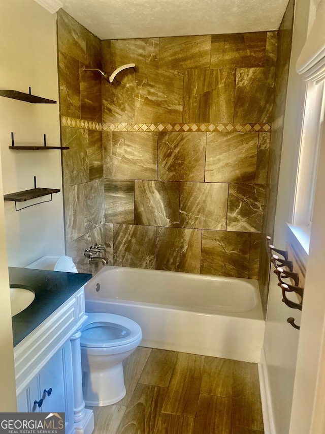 bathroom featuring toilet, vanity,  shower combination, and wood finished floors