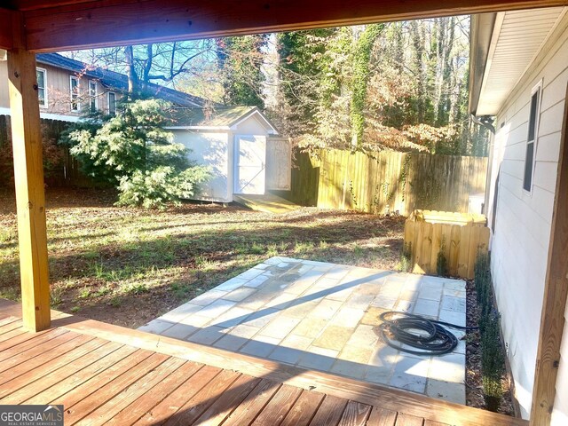 deck featuring a fenced backyard, a storage shed, an outdoor structure, and a patio area