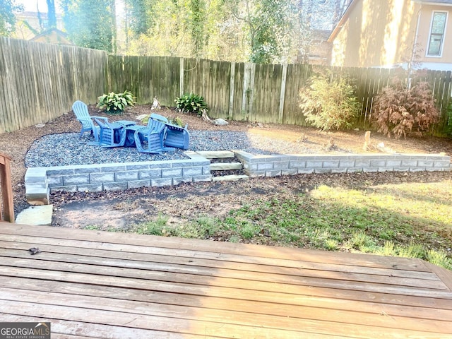 wooden terrace featuring a fire pit and a fenced backyard