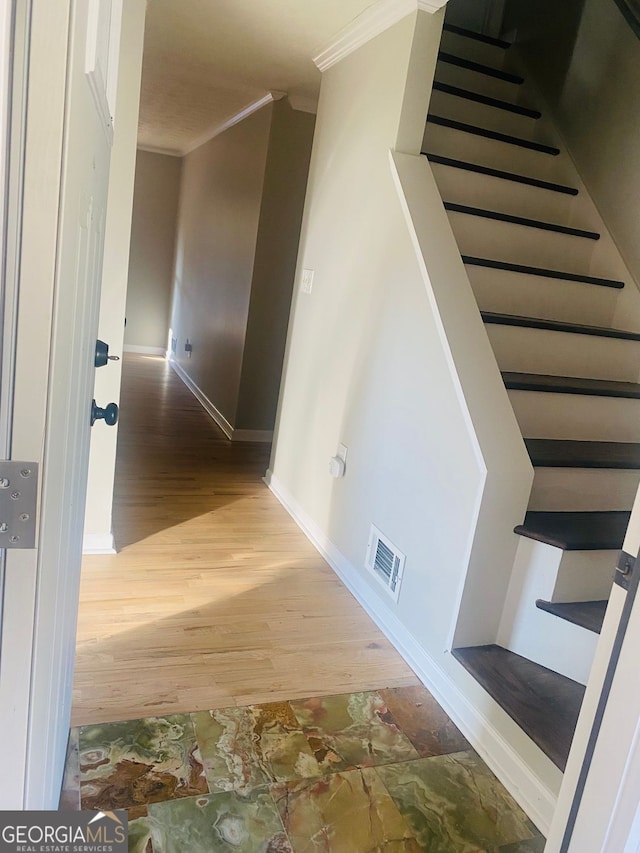 hallway with stairway, wood finished floors, visible vents, and ornamental molding