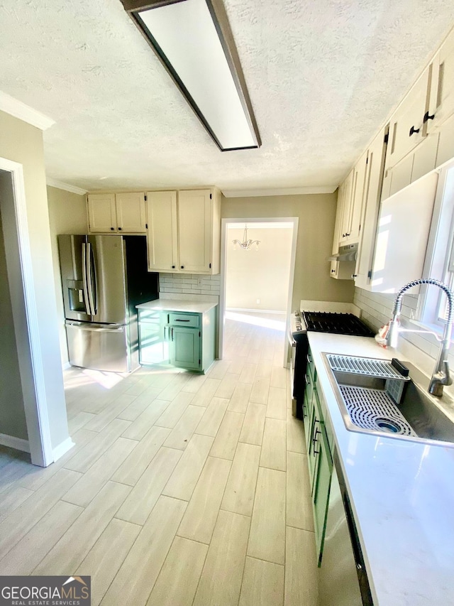 kitchen featuring stainless steel refrigerator with ice dispenser, a sink, range with gas stovetop, tasteful backsplash, and light countertops