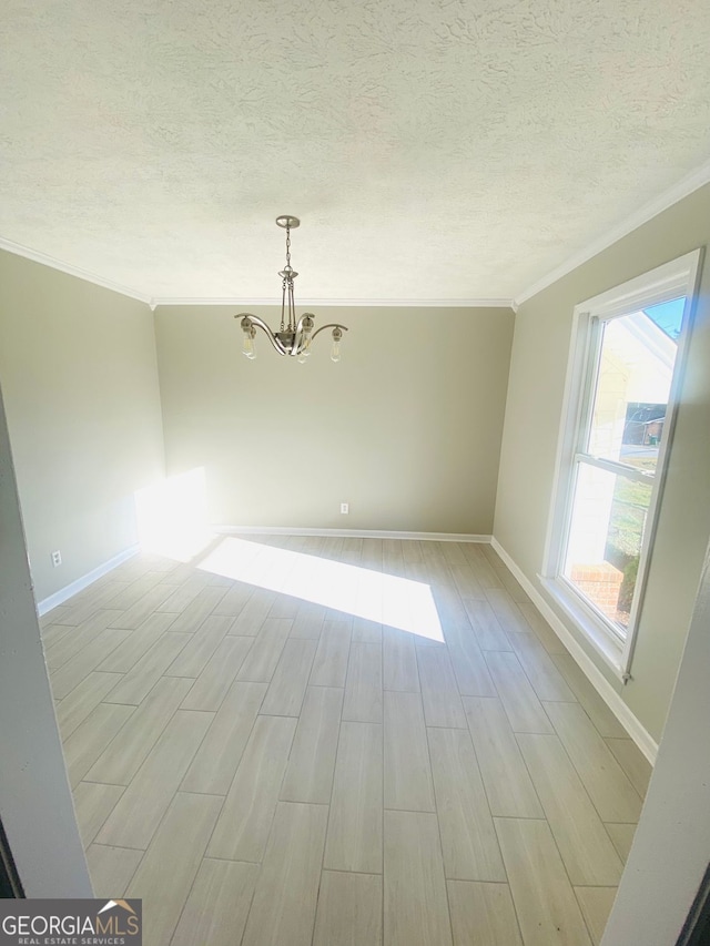 spare room with a textured ceiling, an inviting chandelier, light wood finished floors, and ornamental molding