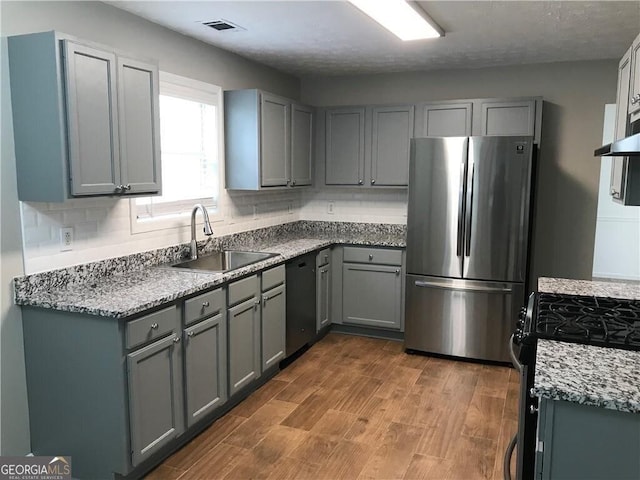 kitchen featuring gray cabinets, freestanding refrigerator, and a sink