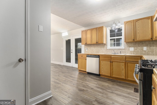 kitchen featuring tasteful backsplash, wood finished floors, stainless steel appliances, and a sink