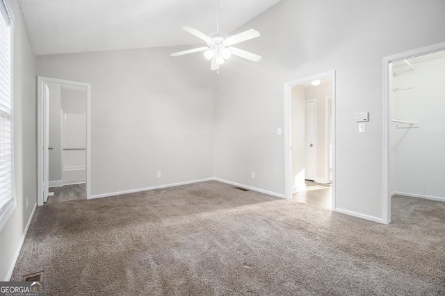 unfurnished bedroom with a spacious closet, baseboards, lofted ceiling, and carpet