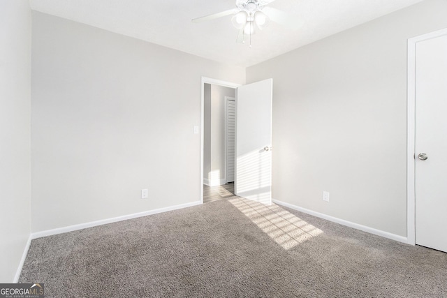 carpeted spare room featuring baseboards and a ceiling fan