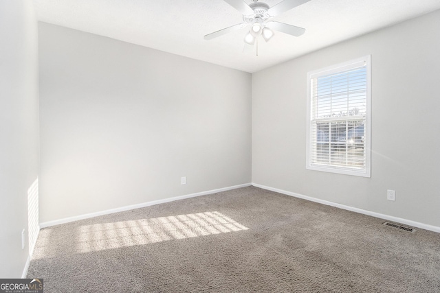 carpeted spare room with visible vents, ceiling fan, and baseboards