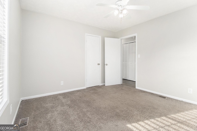 unfurnished bedroom featuring visible vents, baseboards, carpet, and a ceiling fan