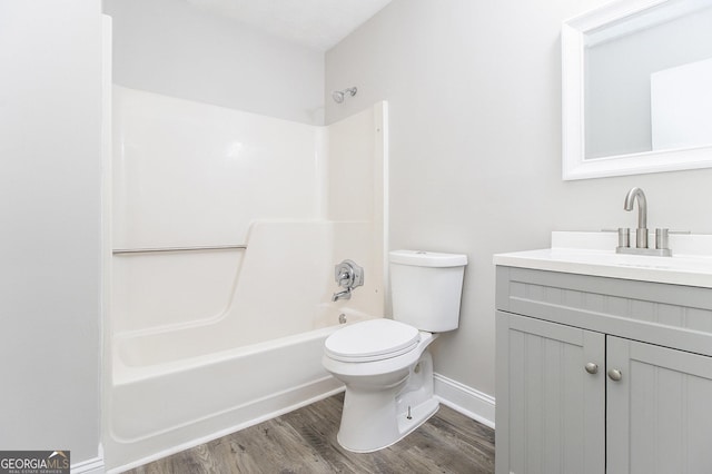 bathroom with baseboards, toilet, shower / bathtub combination, wood finished floors, and vanity