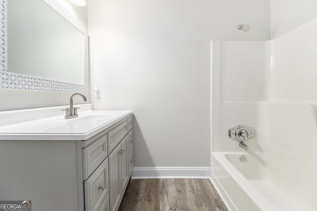 bathroom featuring vanity, wood finished floors, baseboards, and tub / shower combination