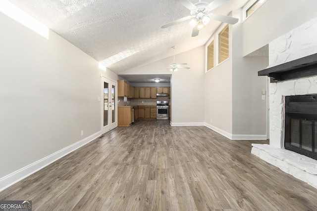 unfurnished living room with wood finished floors, a fireplace, baseboards, and a textured ceiling