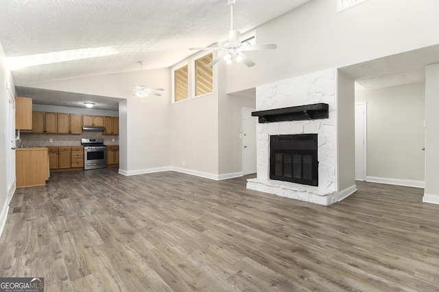 unfurnished living room featuring a stone fireplace, a textured ceiling, wood finished floors, and ceiling fan