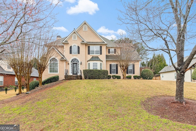 view of front of house featuring stucco siding, a chimney, and a front lawn