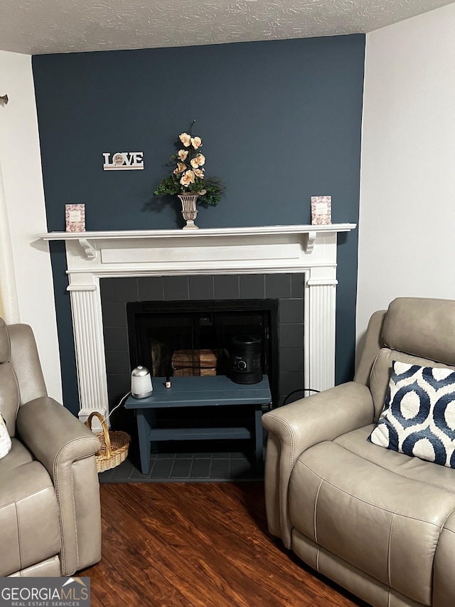 living room featuring a textured ceiling, wood finished floors, and a tile fireplace