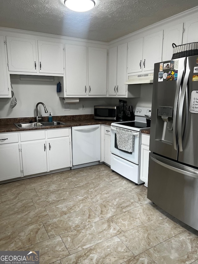 kitchen with a sink, under cabinet range hood, appliances with stainless steel finishes, white cabinetry, and dark countertops