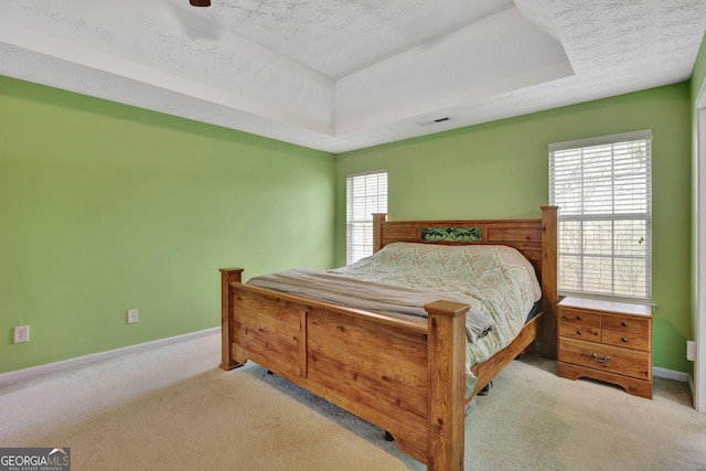 bedroom featuring a raised ceiling, baseboards, visible vents, and carpet floors