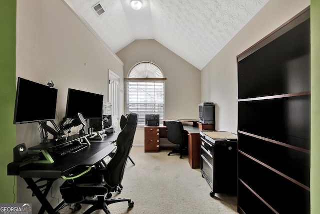 office featuring a textured ceiling, vaulted ceiling, visible vents, and light carpet