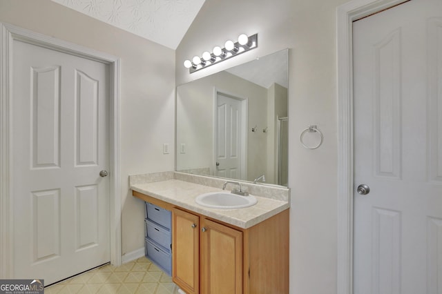 bathroom with tile patterned floors, a textured ceiling, vanity, and lofted ceiling