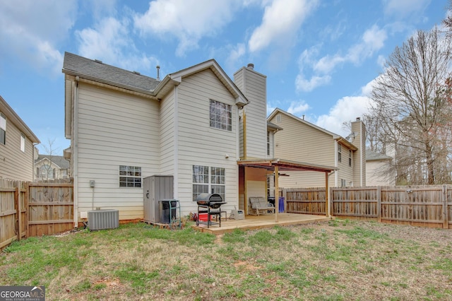 rear view of house with a patio area, central AC unit, a lawn, and a fenced backyard