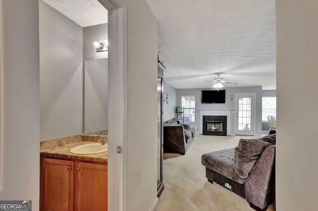 ensuite bathroom with ensuite bathroom, a textured ceiling, ceiling fan, and a fireplace