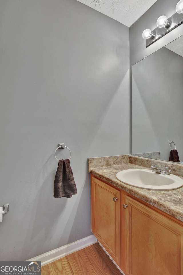 bathroom featuring baseboards, wood finished floors, and vanity