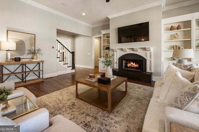 living area featuring stairway, wood finished floors, baseboards, a premium fireplace, and crown molding