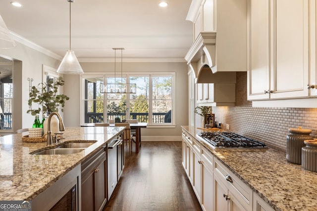 kitchen with backsplash, dark wood finished floors, ornamental molding, appliances with stainless steel finishes, and a sink