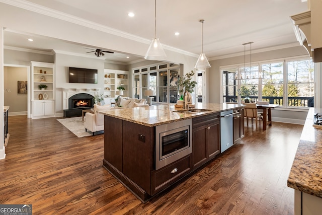 kitchen featuring dark wood-style flooring, a sink, a lit fireplace, dark brown cabinetry, and stainless steel appliances