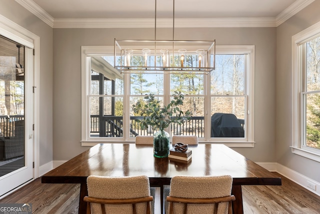 dining space with an inviting chandelier, crown molding, baseboards, and wood finished floors