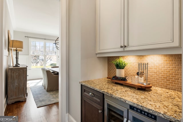 bar with decorative backsplash, beverage cooler, wood finished floors, and ornamental molding