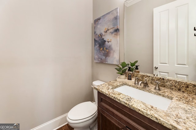 bathroom featuring toilet, vanity, and baseboards