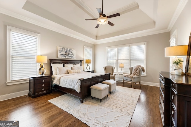 bedroom with a tray ceiling, wood finished floors, crown molding, baseboards, and ceiling fan