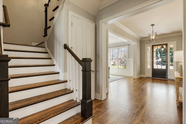 entrance foyer featuring baseboards, a chandelier, stairs, ornamental molding, and dark wood-style flooring