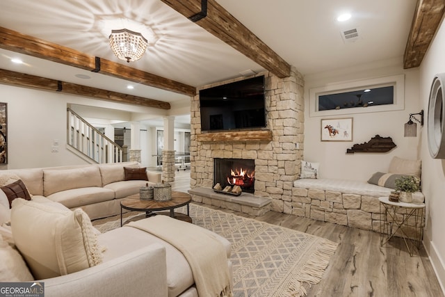 living room featuring visible vents, beamed ceiling, stairway, a fireplace, and wood finished floors