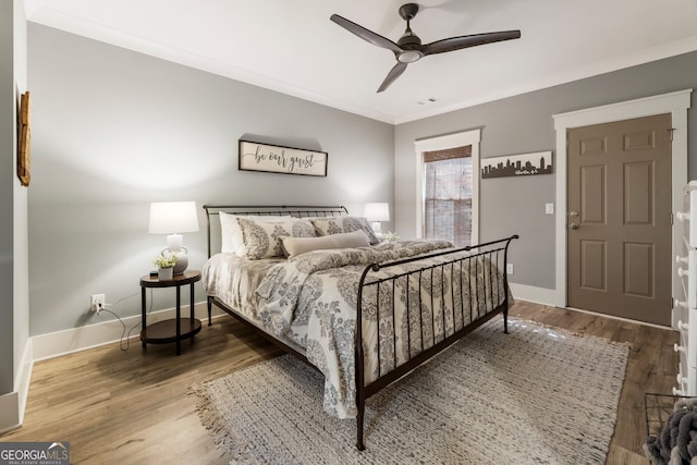 bedroom featuring crown molding, wood finished floors, baseboards, and ceiling fan