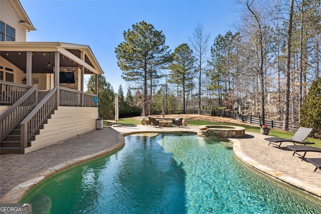 view of pool featuring a ceiling fan, a pool with connected hot tub, a patio, fence, and stairway