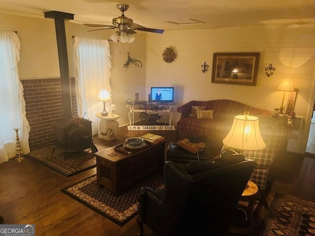 living area featuring a wood stove, a ceiling fan, and wood finished floors