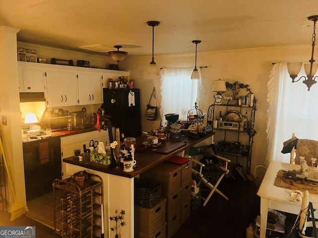 kitchen featuring decorative light fixtures, white cabinetry, dark countertops, and freestanding refrigerator