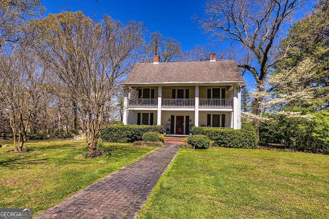 colonial inspired home featuring covered porch, a front lawn, and a balcony