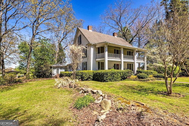 view of property exterior featuring a balcony, a chimney, and a lawn