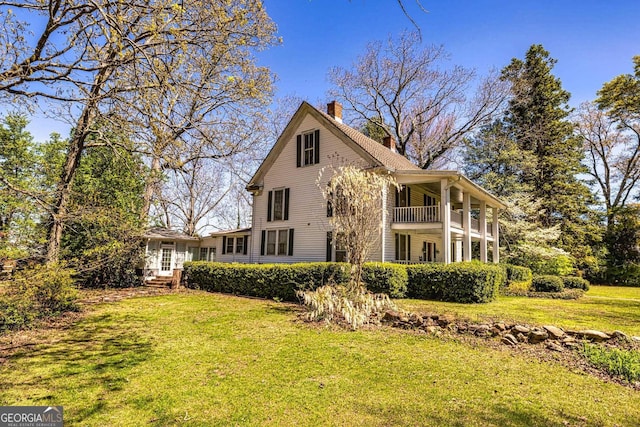 rear view of property featuring a yard, a balcony, and a chimney