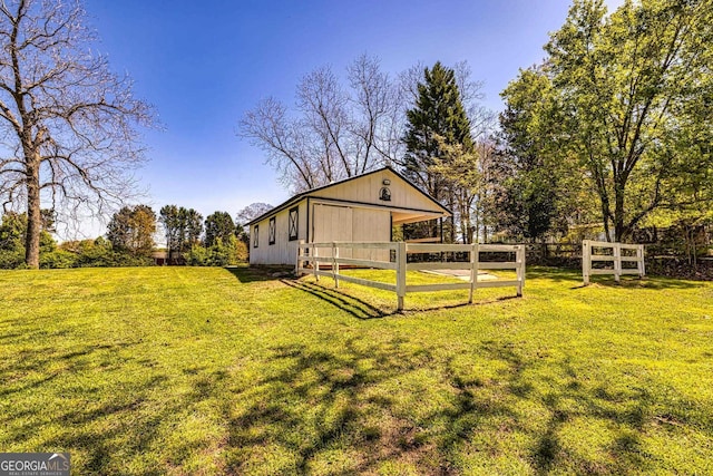 view of pole building with an exterior structure, a yard, and fence