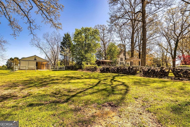 view of yard featuring an outbuilding, fence, and a pole building