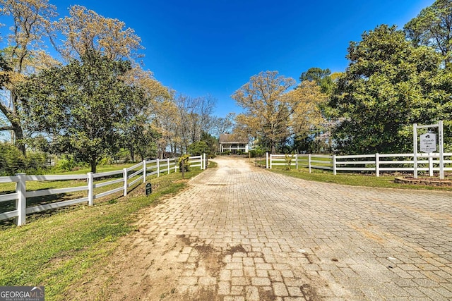 view of road with decorative driveway and a rural view