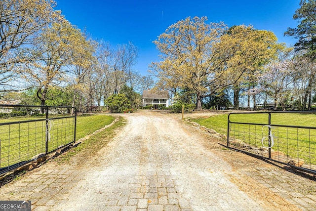 view of street featuring a gate, a rural view, driveway, and a gated entry