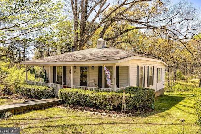 view of front of home with a porch, a chimney, and a front lawn