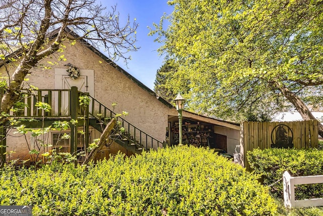 view of property exterior with stairway, fence, and stucco siding