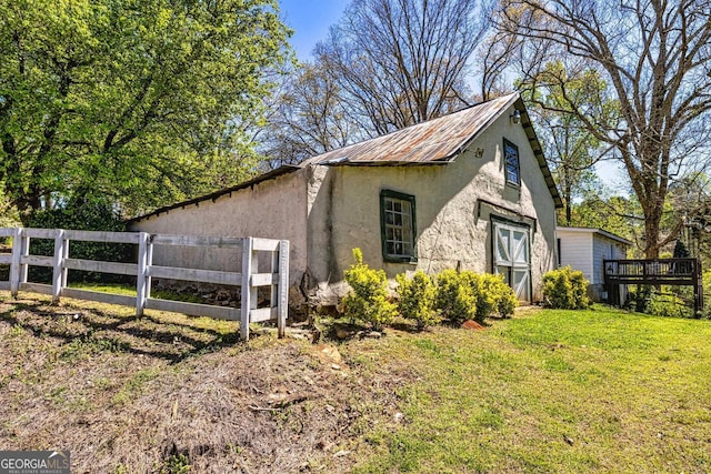 view of property exterior featuring stucco siding, a yard, metal roof, and fence